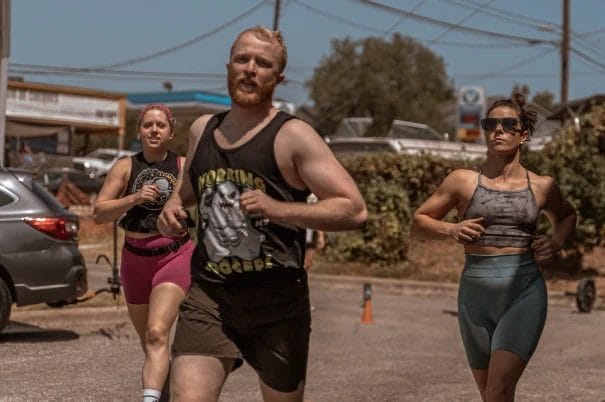 Two women and a man running outside